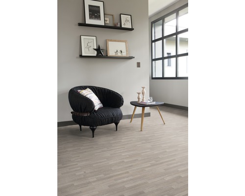 Heller Raum mit einem Sessel, einem Tisch und Regalen an der Wand, der einen organisierten Eindruck vermittelt.