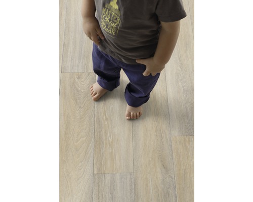 Enfant debout sur un sol stratifié clair aspect bois