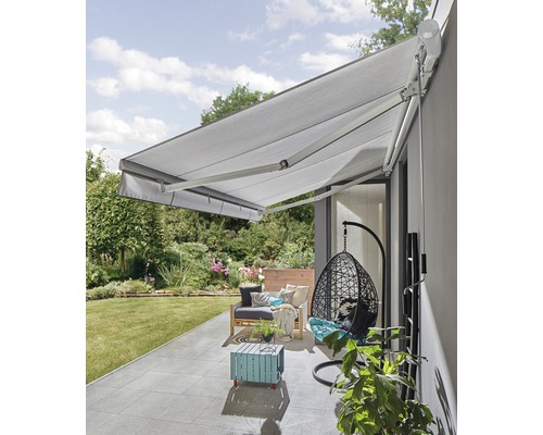 Terrasse avec store, coin salon et fauteuil suspendu dans le jardin