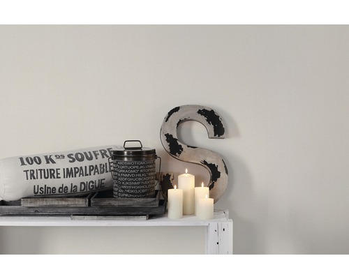 Dekorative Szene mit Kissen, Dose, Buchstaben und Kerzen auf einem weißen Regal