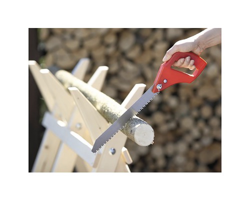 Handsäge beim Sägen eines Holzscheits auf einem Holzbock