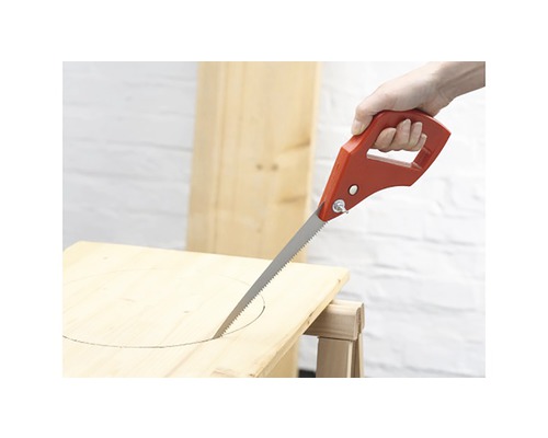 Eine Stichsäge mit rotem Griff schneidet ein Loch in ein Holzbrett.