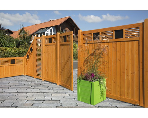 Gartenzaun aus Holz mit Dekorationselementen und einem grünen Pflanzgefäß im Vorgarten eines Wohnhauses.