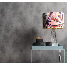 Szene mit floral gemusterter Lampe auf einem Beistelltisch vor einer grauen Wand