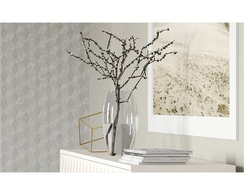 Dekorative Szene mit Vase, Ästen, geometrischer Dekoration und Bilderrahmen auf einem Sideboard vor einer gemusterten Tapete