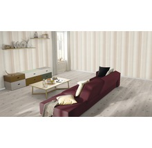 Wohnzimmer mit Sofa, Tisch, Kommode und Wandregalen vor gestreifter Tapete