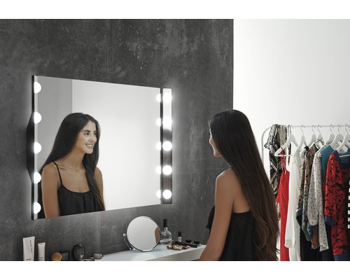 Femme devant un miroir de maquillage éclairé dans la salle de bain.