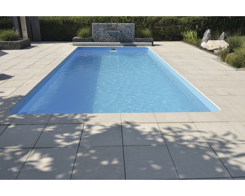 Rechteckiger Pool umgeben von Steinplatten im Garten