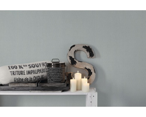 Dekorative Szene mit Kissen, Dose, Holzbuchstabe und Kerzen auf einem Regal.