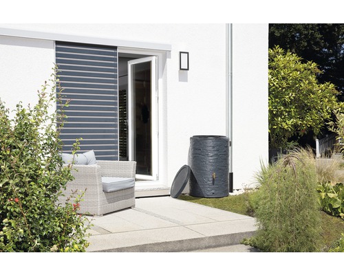 Récupérateur d''eau de pluie sur une terrasse à côté d''une maison avec jardin