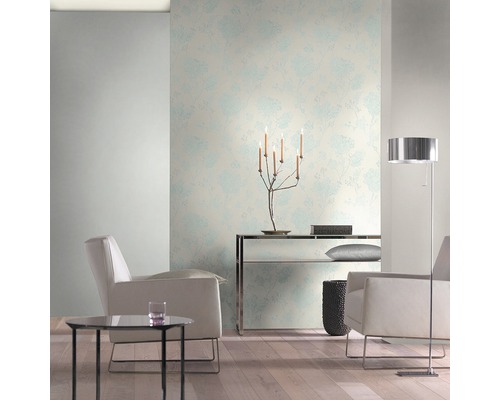 Heller Wohnraum mit floral gemusterter Tapete, Sesseln und Stehlampe.