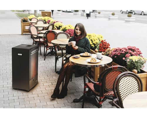 Femme buvant du café sur une terrasse avec chauffage de terrasse et fleurs