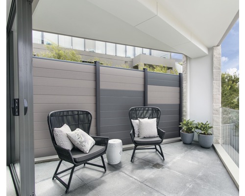 Balcon avec deux chaises, coussins, une petite table, plantes et une clôture