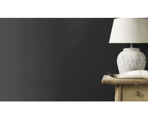 Scène décorative avec lampe, corne et commode en bois sur fond de mur sombre.