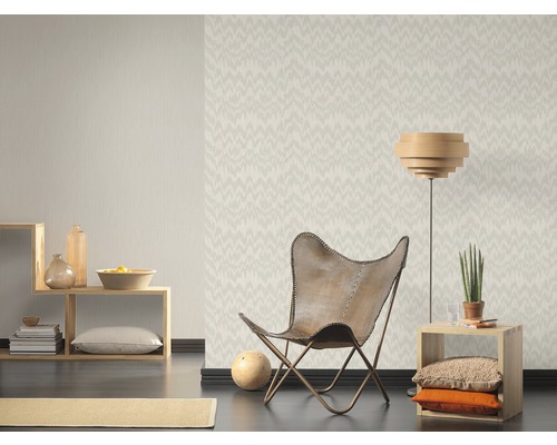 Wohnzimmer mit gemusterter Tapete, Sessel und Holzmöbeln