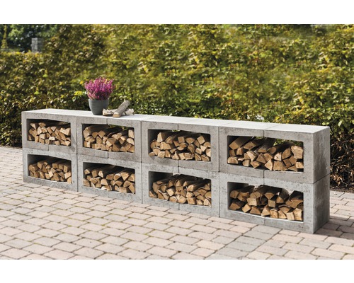 Stockage de bois en blocs de béton avec des bûches et une plante en pot