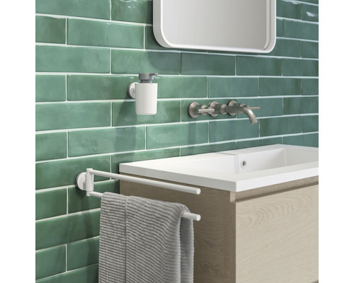 Vue d''une salle de bains avec lavabo, robinet, distributeur de savon et porte-serviettes devant un carrelage mural