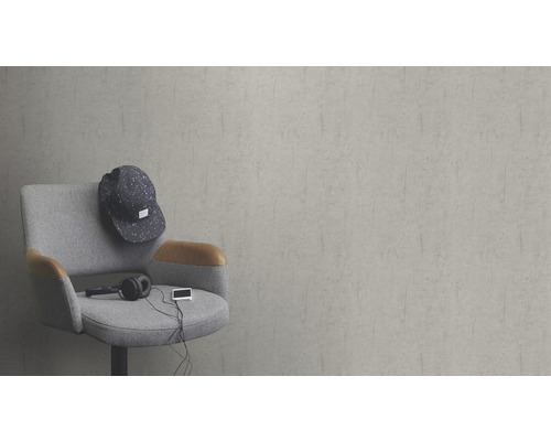 Szene mit einem grauen Sessel, einer Mütze, Kopfhörern und einem Musikabspielgerät vor einer grauen Wand.