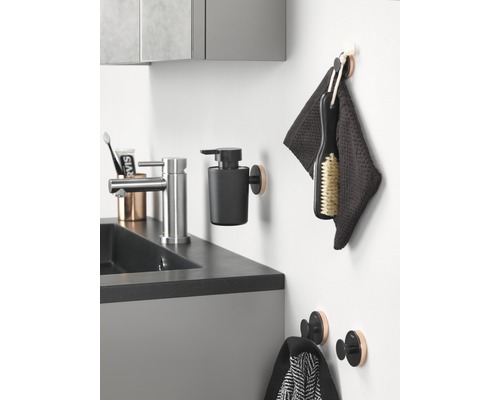 Coin lavabo de salle de bains avec robinet, distributeur de savon, serviettes et crochets.