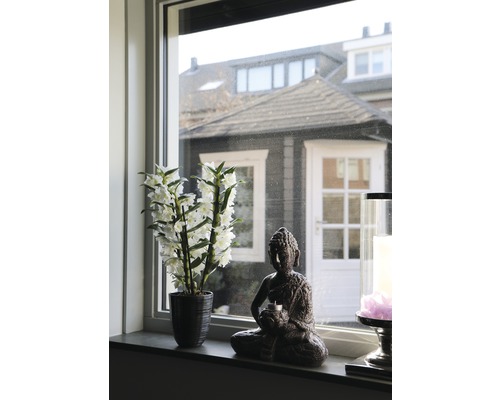 Dekoration mit Kunstpflanze, Buddhafigur und Kerze auf einer Fensterbank