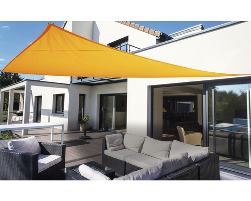 Dreieckiges Sonnensegel über einer Terrasse mit Gartenmöbeln und einem Wohnhaus