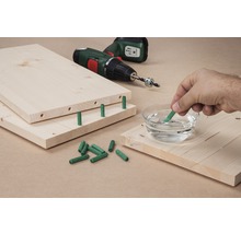 Planches en bois avec chevilles, perceuse et main trempant une cheville dans l''eau