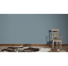 Wohnszene mit Holzfußboden, Kuhfellteppich und Holzstuhl vor einer Wand