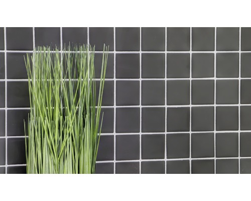 Dekorative Kunstpflanze vor einer Wand aus Fliesen