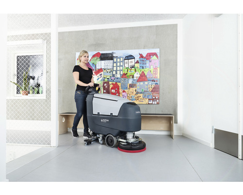 Femme utilisant une autolaveuse dans une pièce