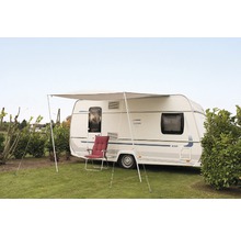 Wohnwagen mit Markise und Campingstuhl auf einer Wiese