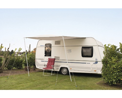 Wohnwagen mit Markise und Campingstuhl auf einer Wiese