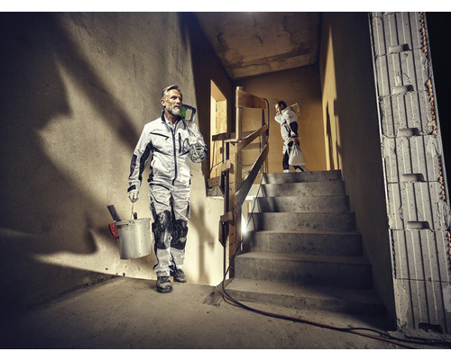 Artisans en vêtements de travail avec des outils et du matériel sur un chantier de construction.