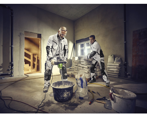 Deux artisans travaillent dans une pièce avec des marchandises en sac et un mélangeur de mortier.