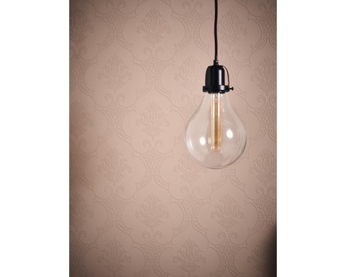 Dekorative Glühbirne mit durchsichtigem Glas vor einer Wand mit floralem Muster