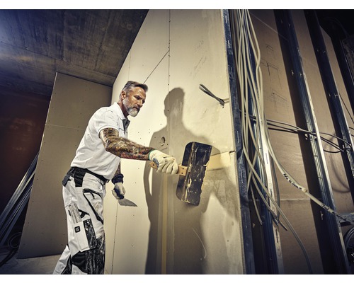 Artisan enduisant un mur sur un chantier