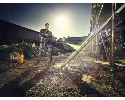 Un homme nettoie un échafaudage avec un nettoyeur haute pression sur un chantier.