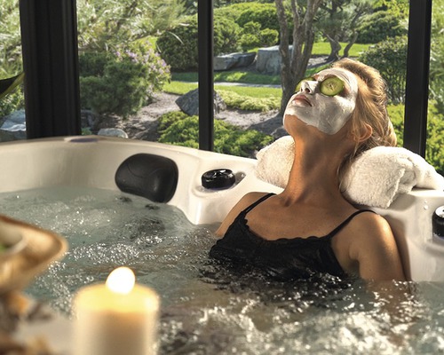 Frau entspannt mit Gesichtsmaske und Gurkenscheiben in einem Whirlpool im Garten.