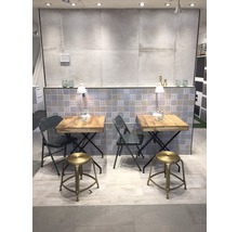 Salle d''exposition avec deux tables et des sièges, fond carrelé et éclairage.