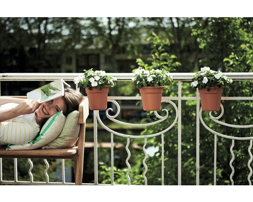 Frau entspannt auf einer Bank auf dem Balkon mit Blumenkästen am Geländer