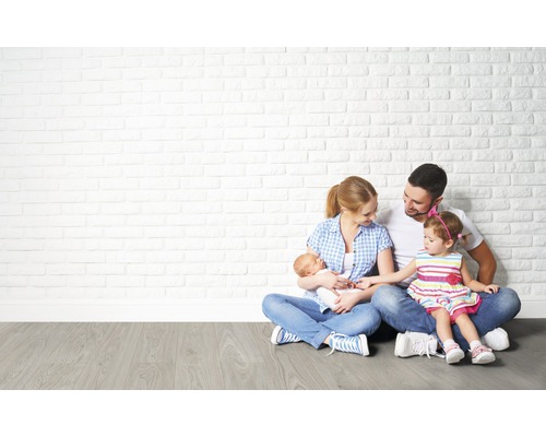 Famille assise par terre devant un mur de briques blanches