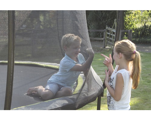 Deux enfants jouent sur un trampoline de jardin avec filet de sécurité