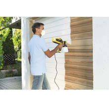 Homme peignant un mur en bois avec un système de pulvérisation de peinture