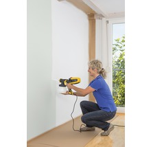 Femme utilisant un système de pulvérisation de peinture pour les murs intérieurs.