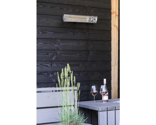Terrassenszene mit Heizstrahler, Tisch, Weinflasche und Gläsern vor dunkler Holzvertäfelung