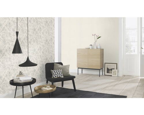 Salon avec papier peint à motifs, fauteuil noir et deux suspensions