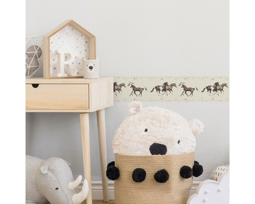 Chambre d''enfant avec bordure à motif de cheval, table en bois et peluches.
