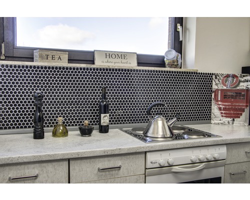 Küchenszene mit Spüle, Herd, Armaturen und Küchenutensilien vor schwarzem Mosaikhintergrund