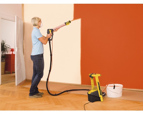 Femme utilisant un système de pulvérisation de peinture pour peindre un mur