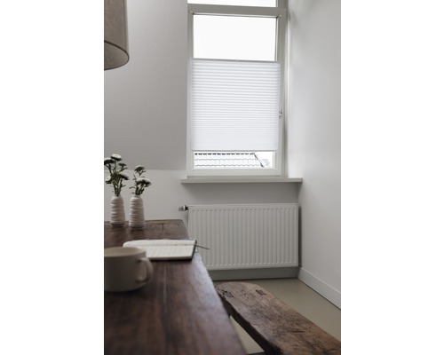 Wohnraum mit Tisch, Bank und Plissee am Fenster für Sicht- und Sonnenschutz