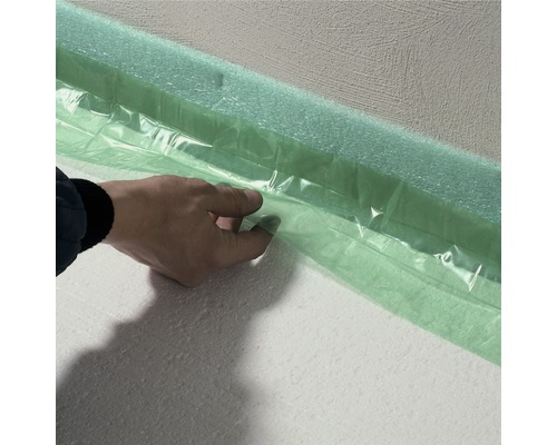 Person befestigt Randdämmstreifen an einer Wand